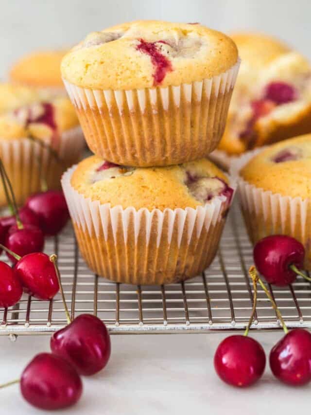 2 cherry muffins stacked and placed on a cooling rack