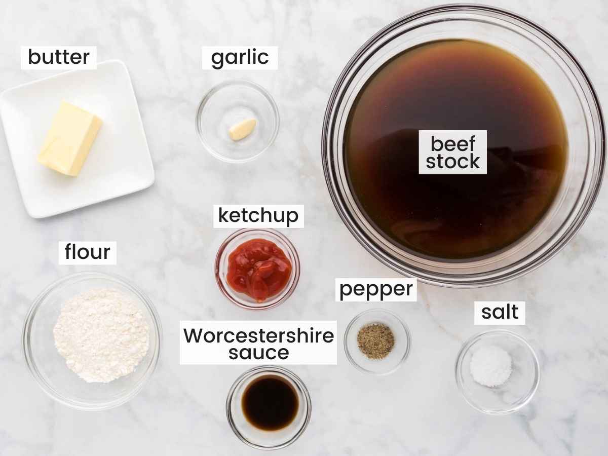 Ingredients needed to make brown gravy including beef stock, flour, garlic, butter, Worcestershire sauce, ketchup, salt and pepper.