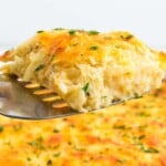 A slice of cheesy casserole being served from the casserole dish