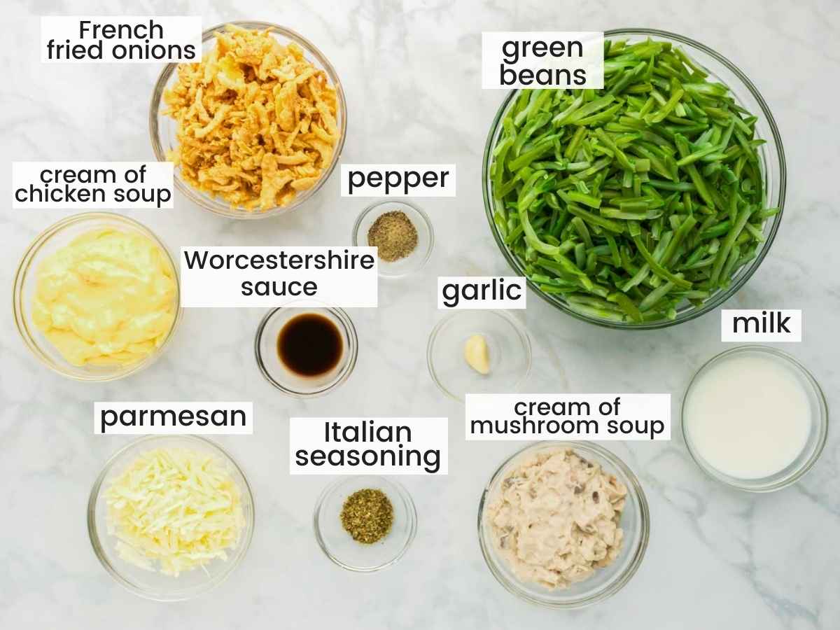 Ingredients needed to make green bean casserole including green beans, fried onions, cream of mushroom soup, cream of chicken soup, parmesan, milk, garlic and seasonings.