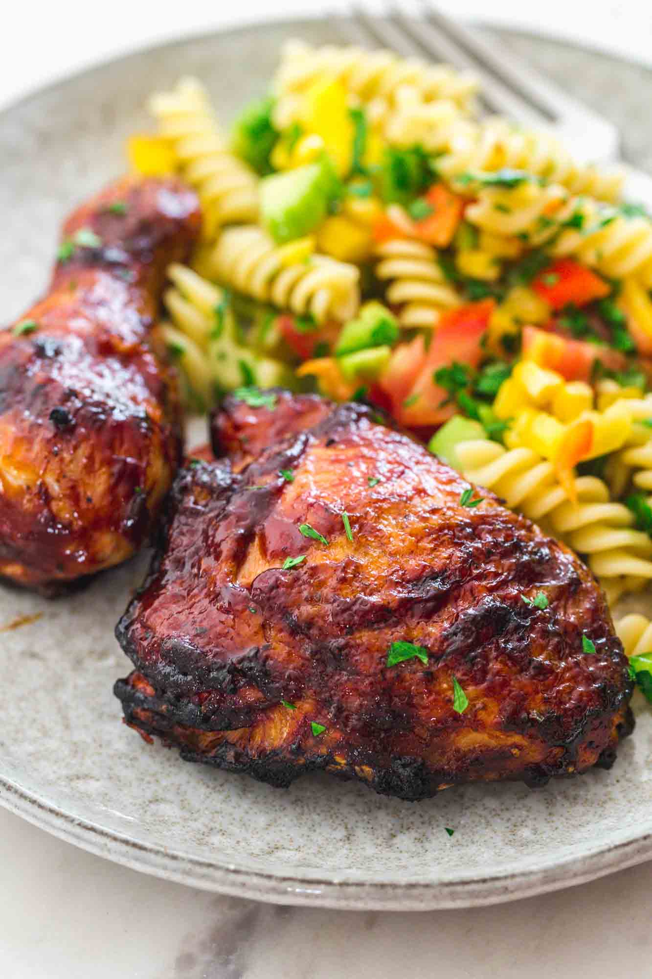 Grilled BBQ Chicken thigh and drumstick served in a plate with pasta salad