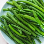 Overhead shot of blanched green beans on a blue side plate