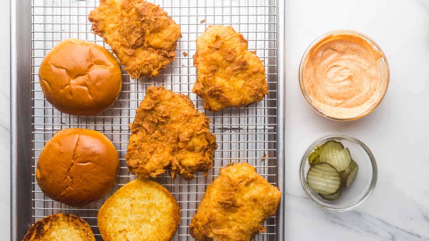 Overhead shot of crispy popeyes chicken with brioche buns, spicy mayo, and dill pickles.