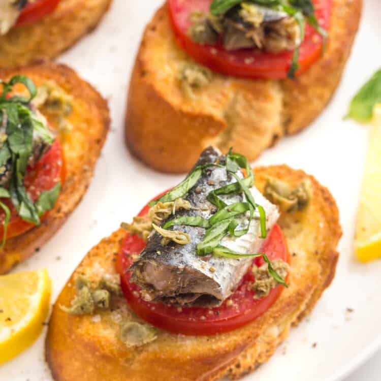 Sardines on Toast with tomato slices, capers, and basil.