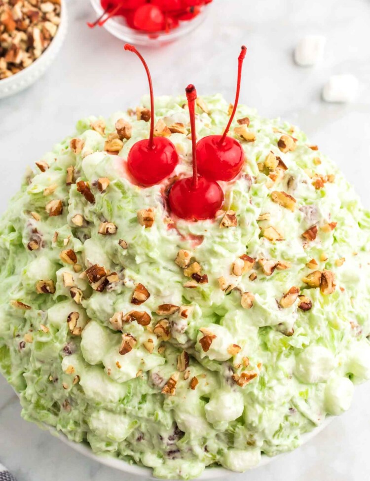 Watergate salad served in a large bowl, and topped with maraschino cherries.