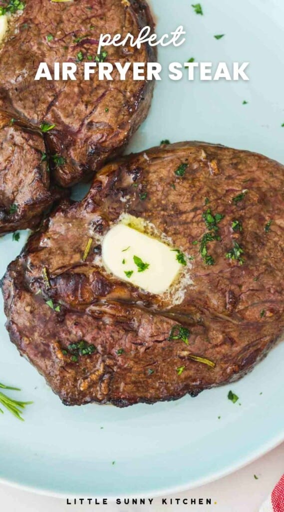 2 steaks on a plate topped with pieces of butter, and overlay text "perfect air fryer steak"