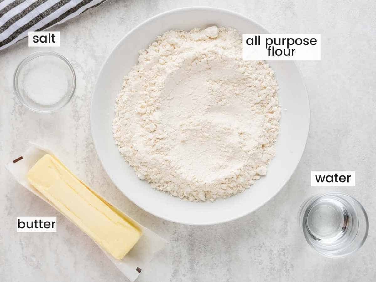Ingredients needed to make pie crust including a stick of butter, flour, salt, water.