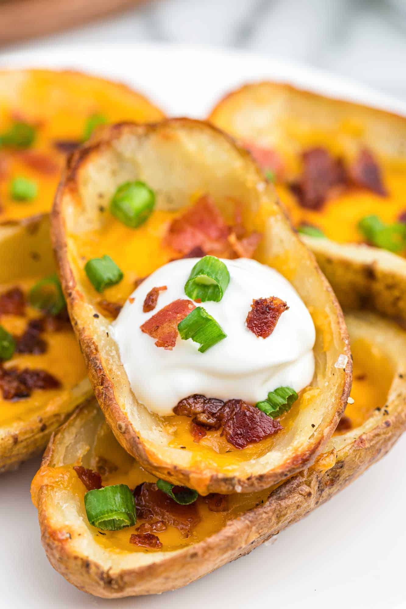 Close up shot of baked potato skins with sour cream, bacon, and green onions.