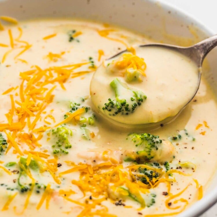 Broccoli cheddar soup served in a white bowl, with a soup spoon