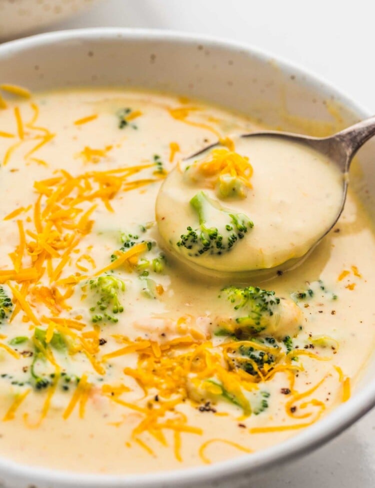 Broccoli cheddar soup served in a white bowl, with a soup spoon
