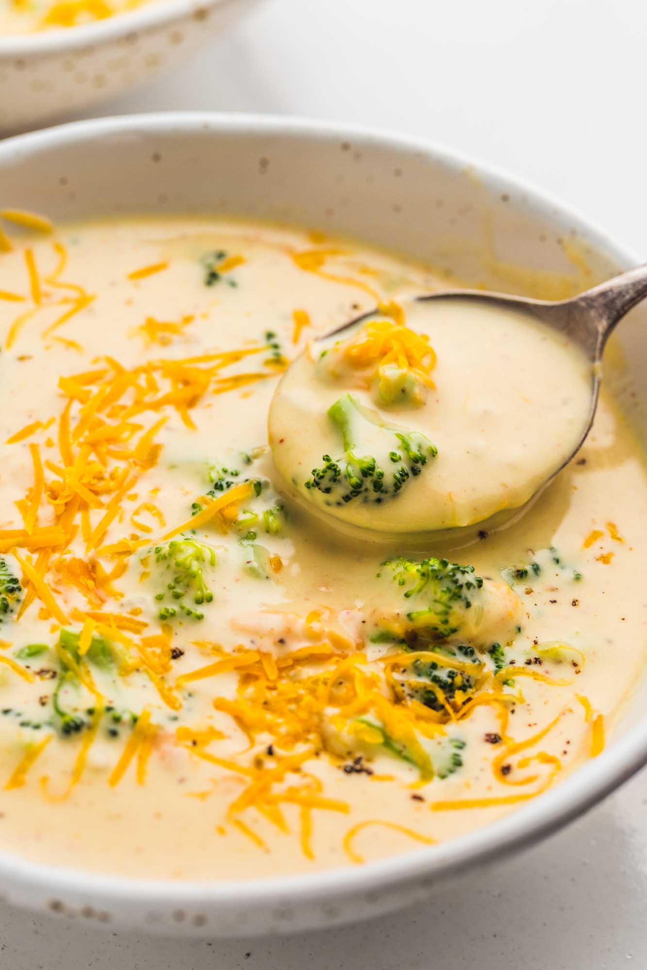 Broccoli cheddar soup served in a white bowl, with a soup spoon