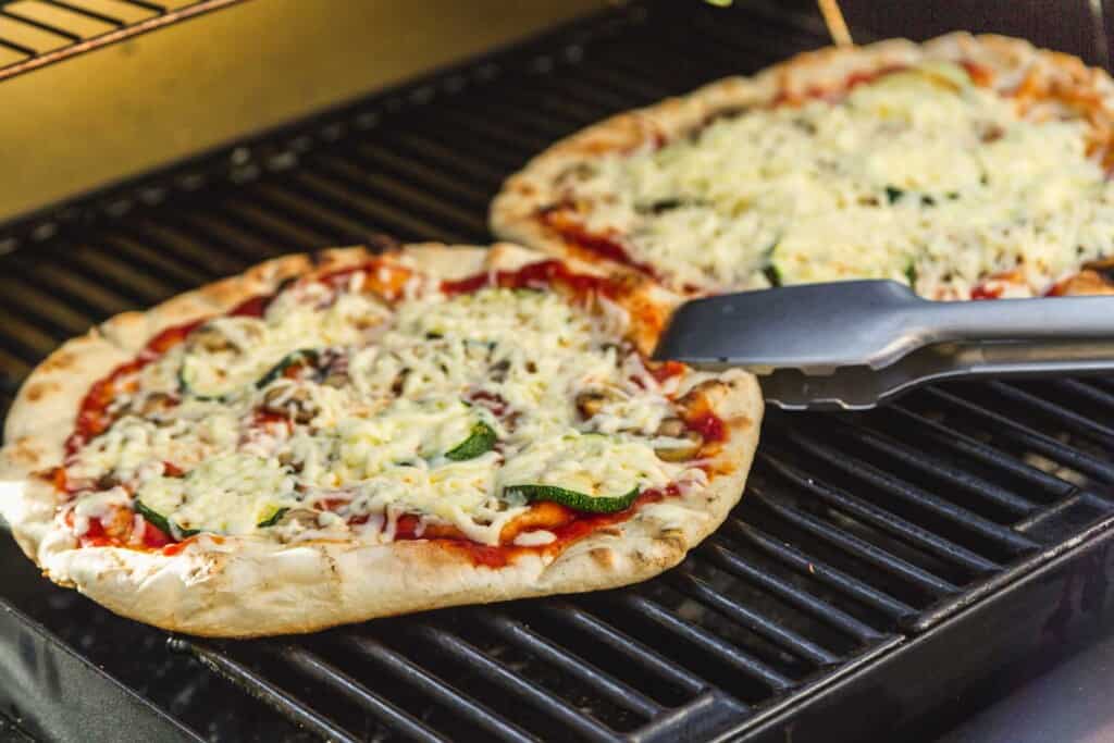 Flipping pizzas on the grill with tongs