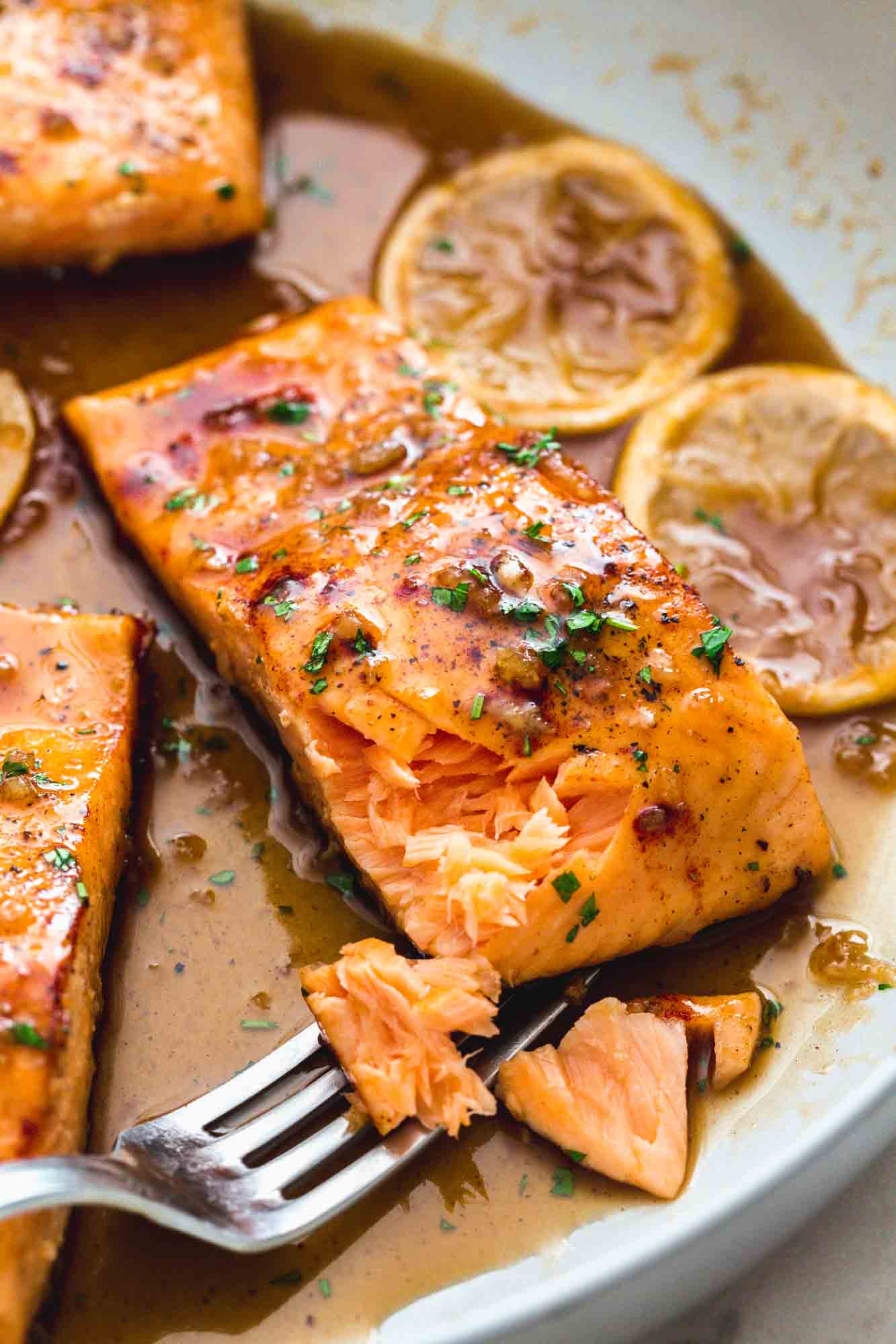 butter and dill roasted salmon fillets on a plate being scooped with a fork