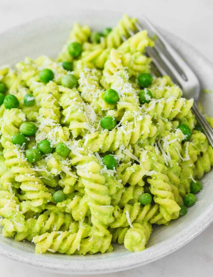 Green pasta with peas in a bowl and fresh peas