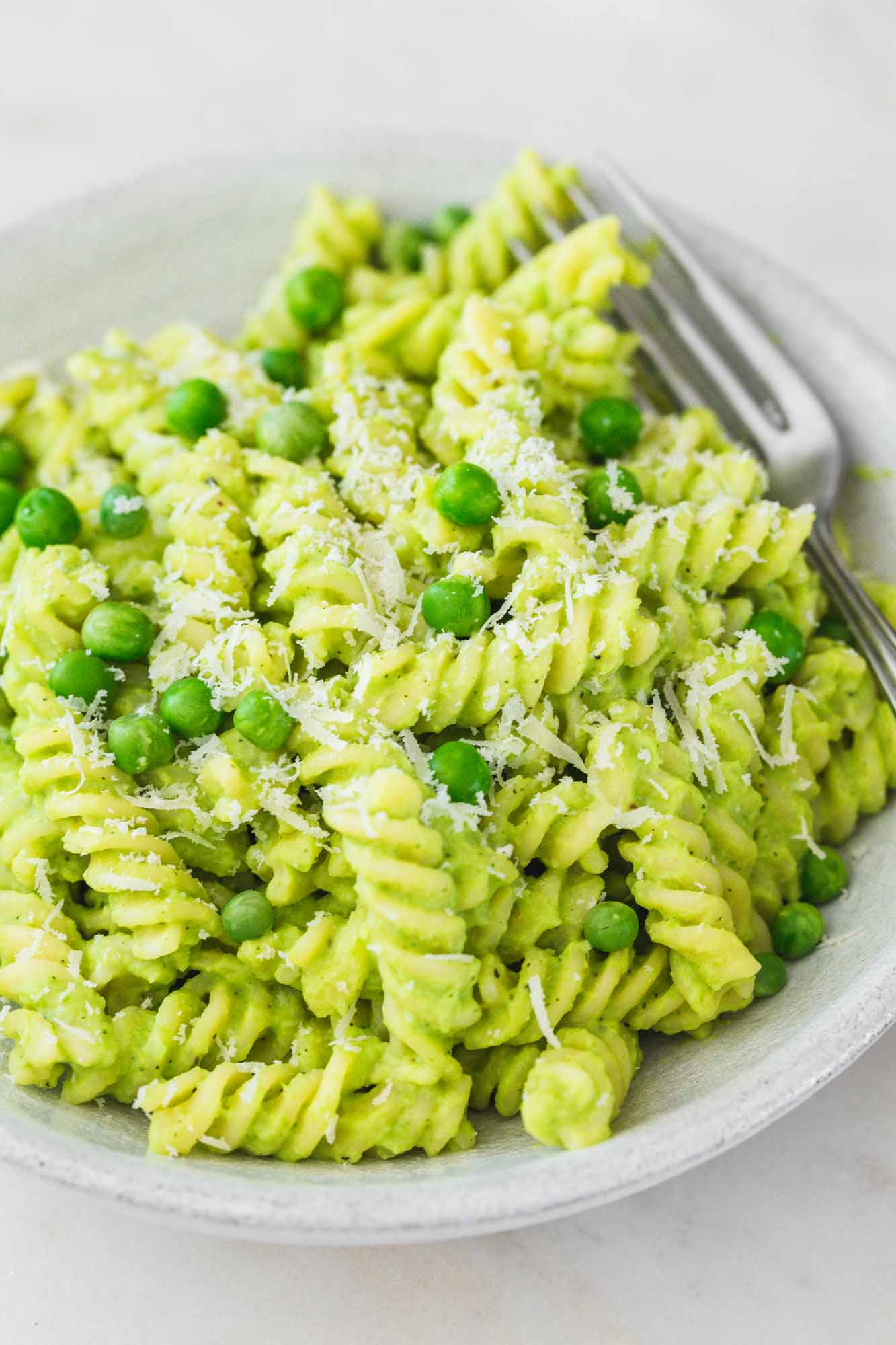 Green pasta with peas in a bowl and fresh peas
