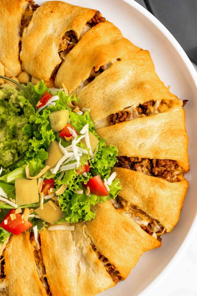 Overhead shot of a taco ring served with salad and guacamole in the middle