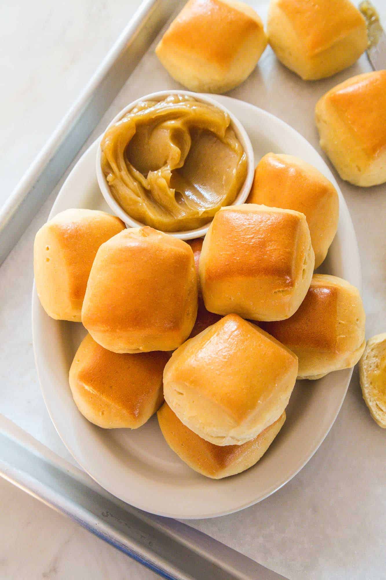 Overhead shot of Texas Roadhouse rolls on a white platter with the cinnamon honey butter