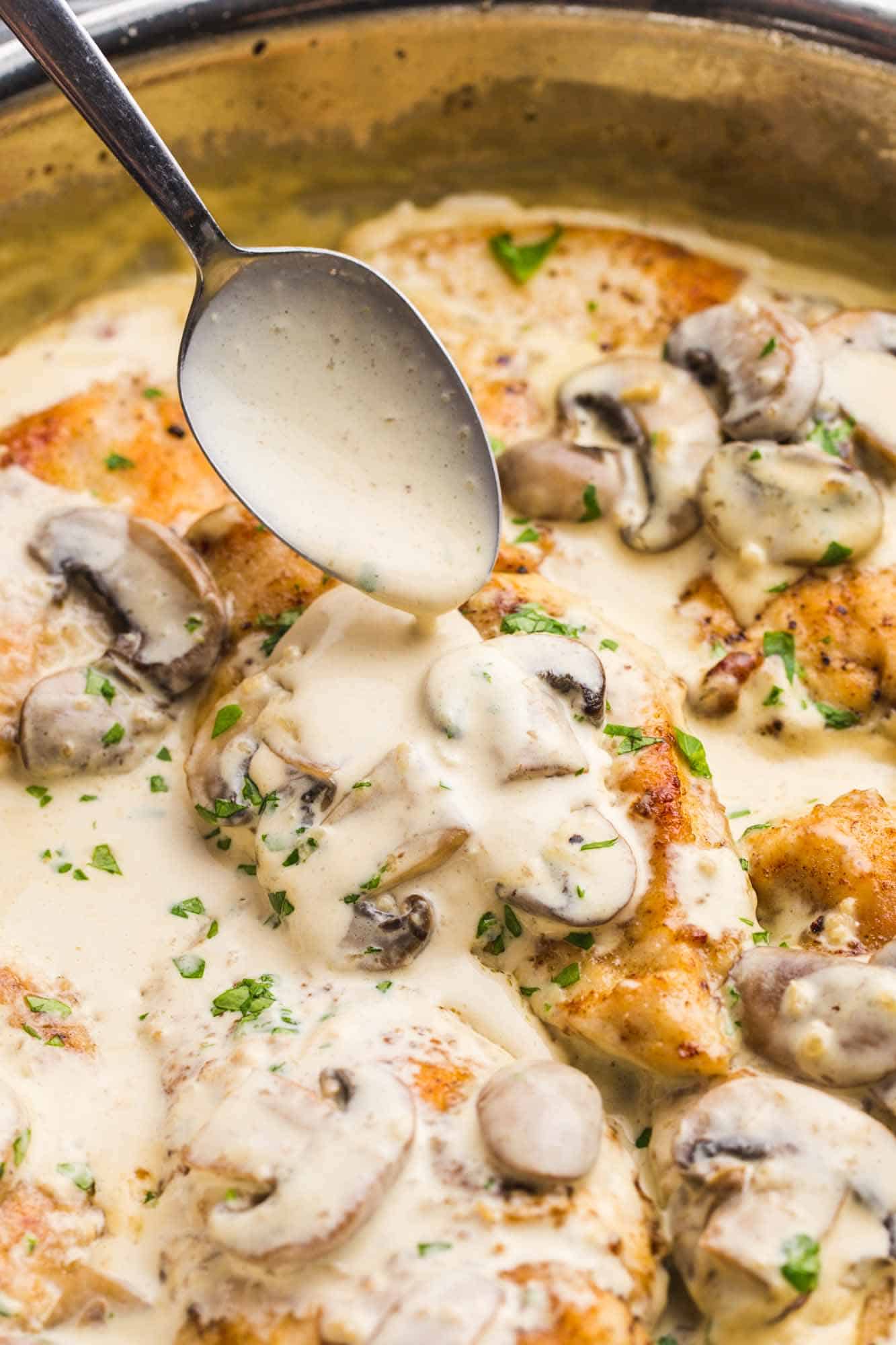 Drizzling mushroom cream sauce over the chicken with a spoon