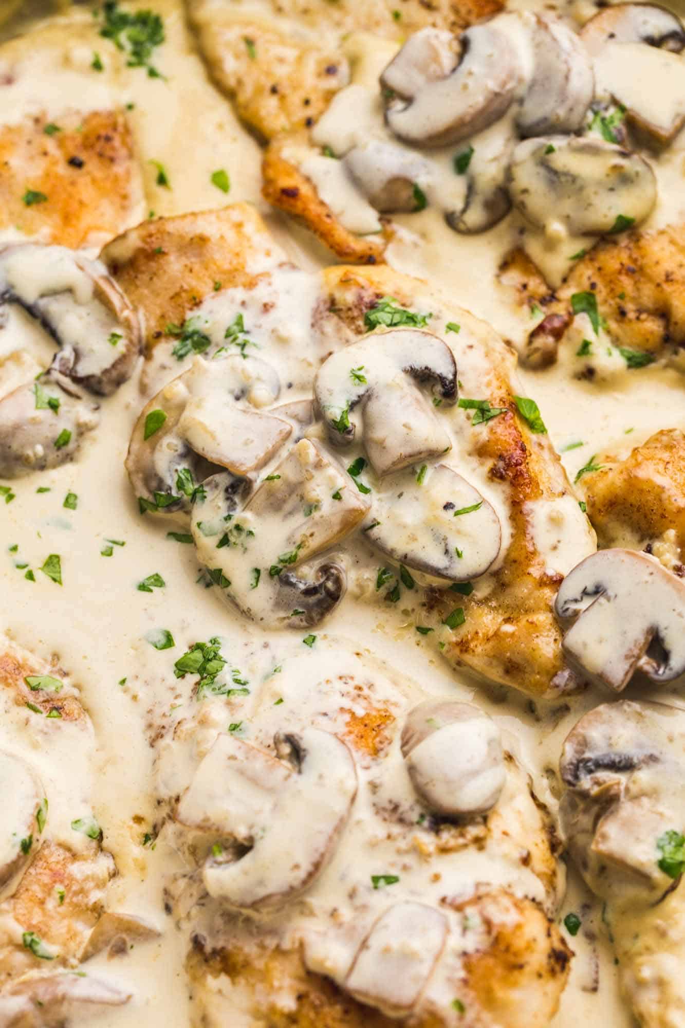 Close up shot of creamy mushroom chicken in a skillet garnished with parsley