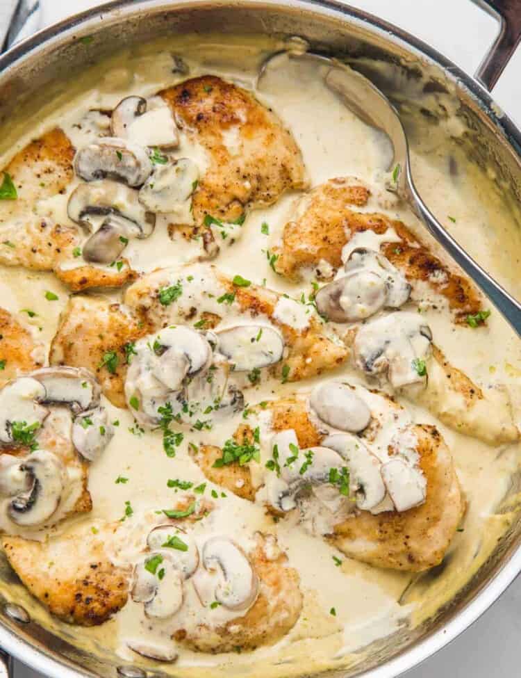 Creamy mushroom chicken in a skillet garnished with parsley in a stainless steel skillet