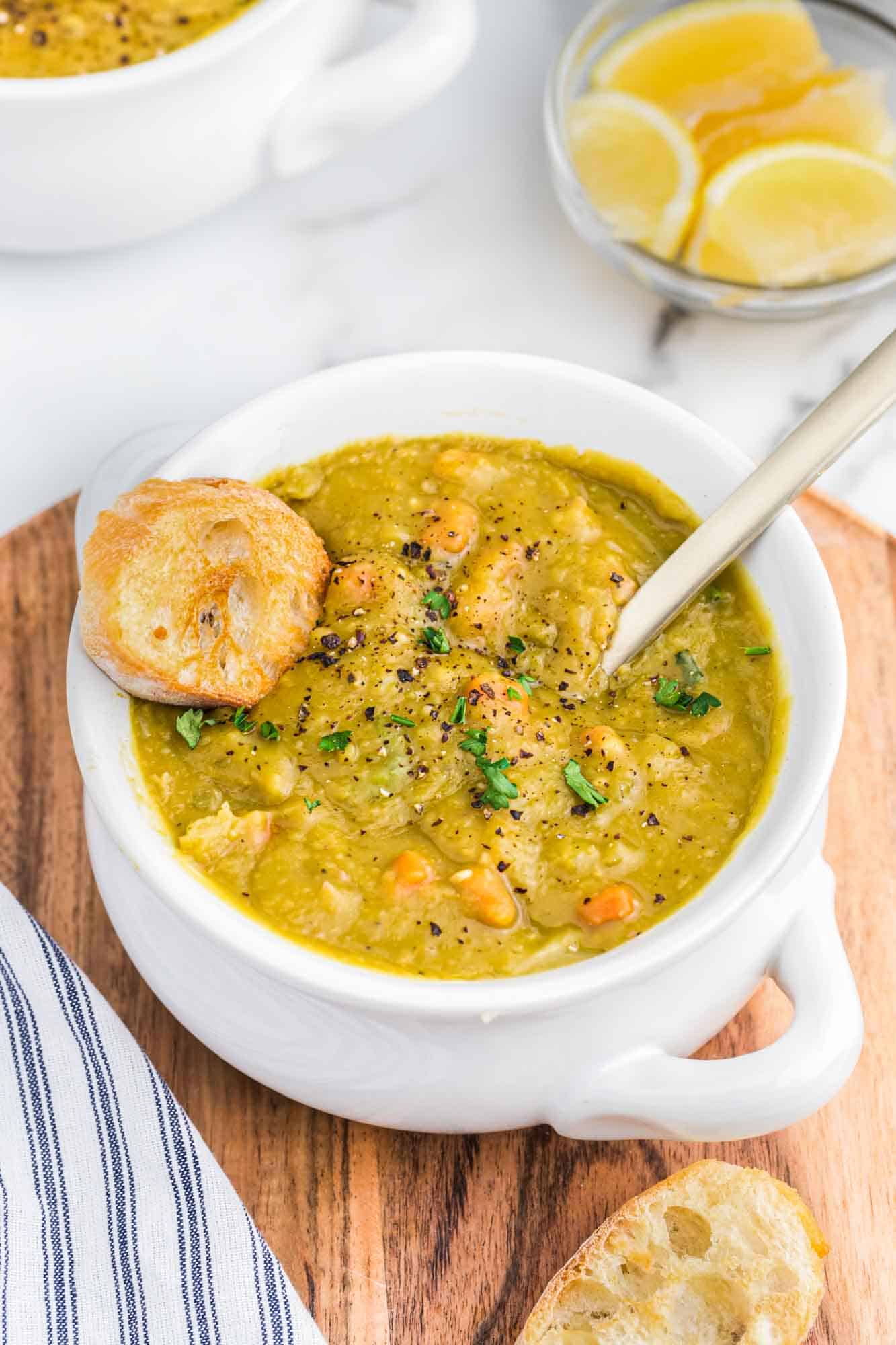 Split pea soup in a white bowl with toasted crusty bread and a spoon