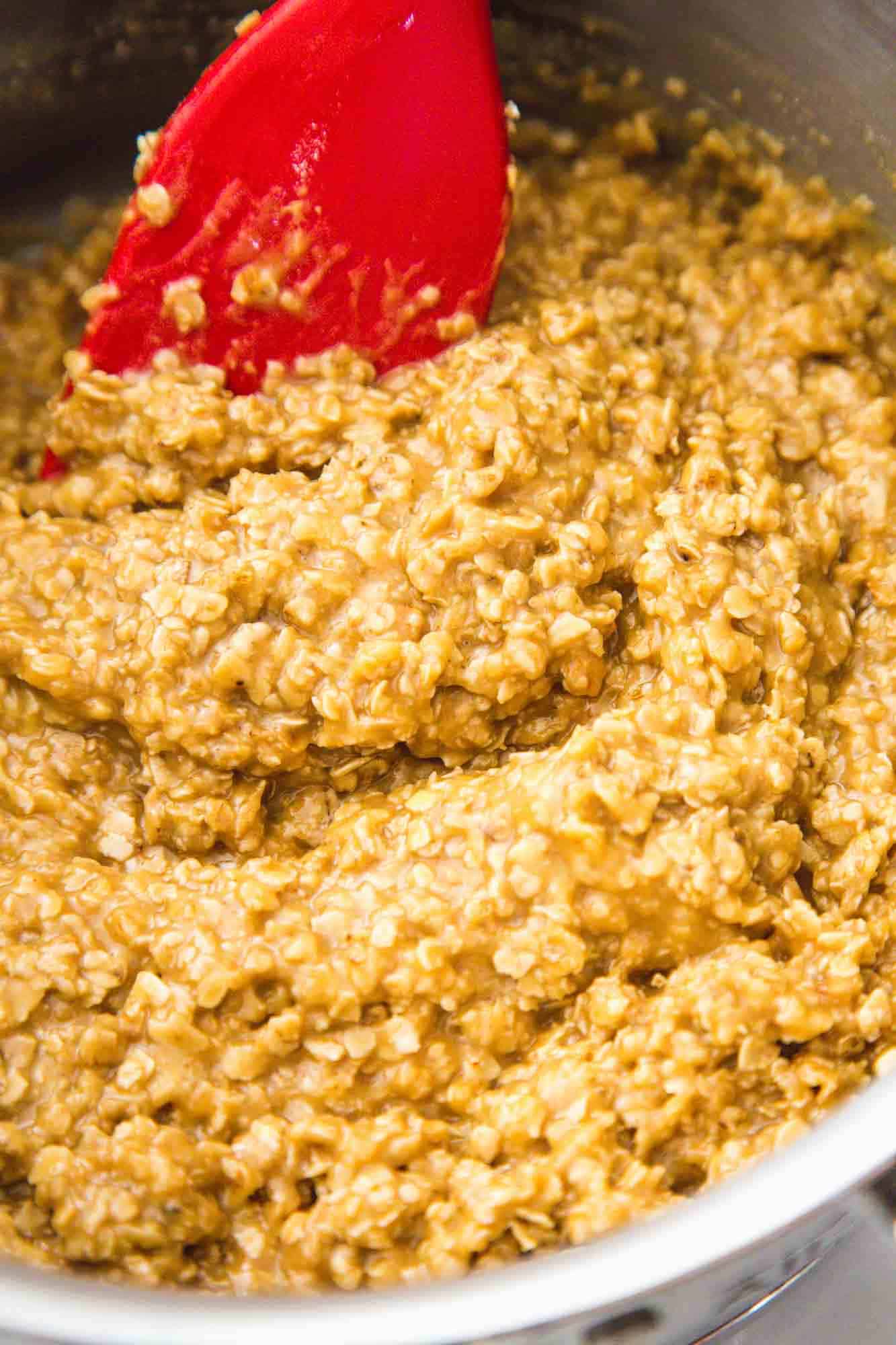 No bake peanut butter cookies mixture in a saucepan with a red spatula