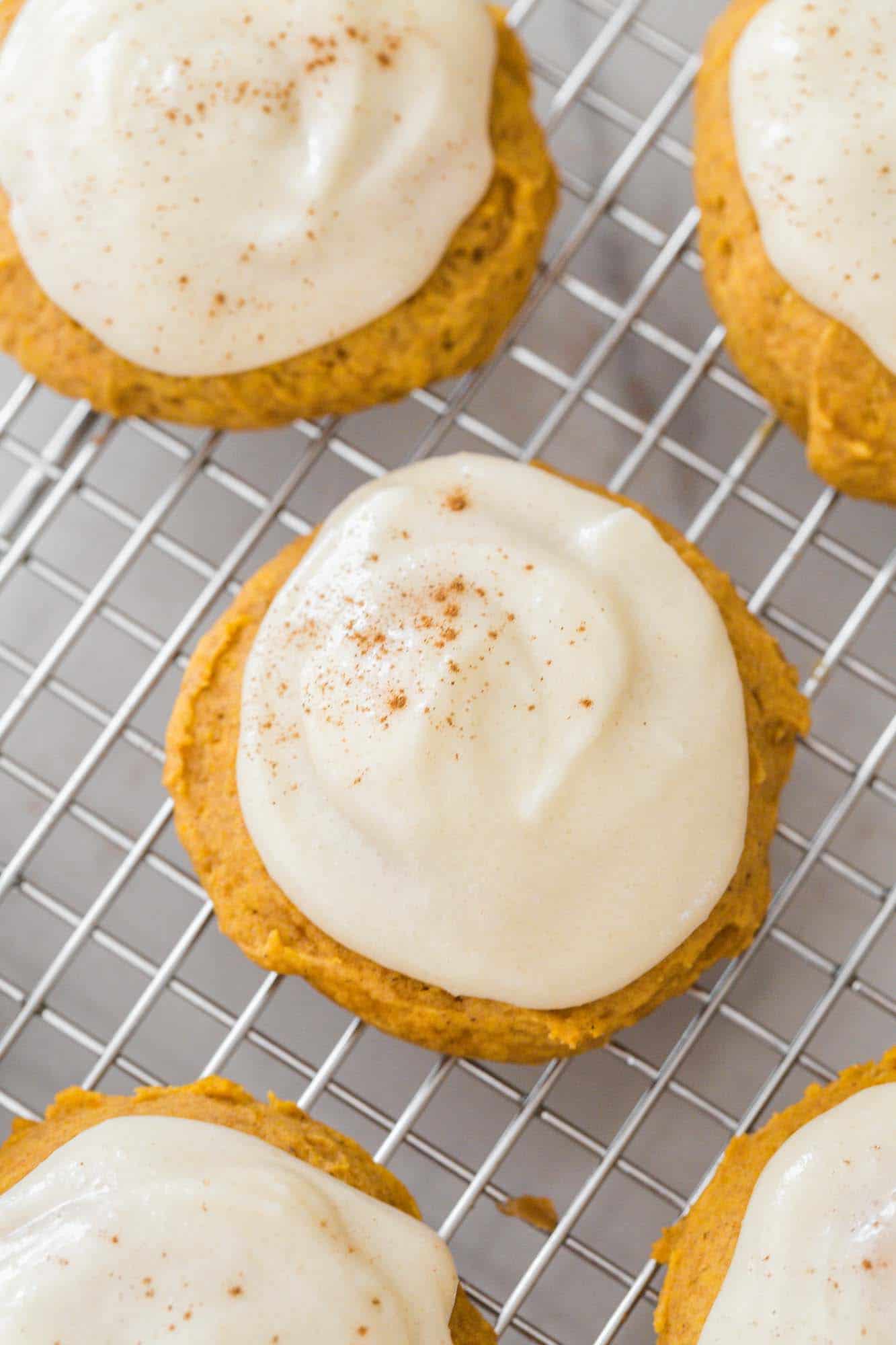 Overhead shot of pumpkin cookies with cream cheese frosting placed on a wire rack