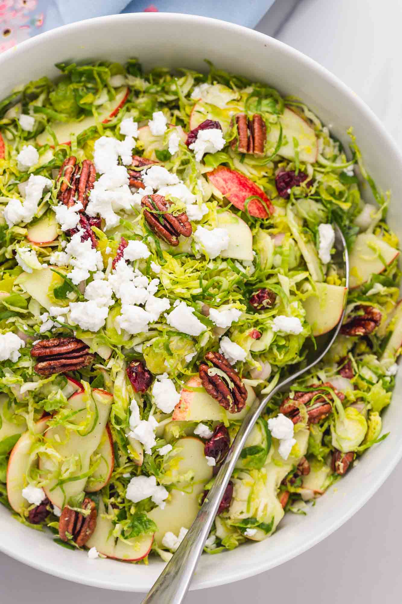 Overhead shot of Shaved Brussels Sprout Salad with goat cheese served in a large salad bowl