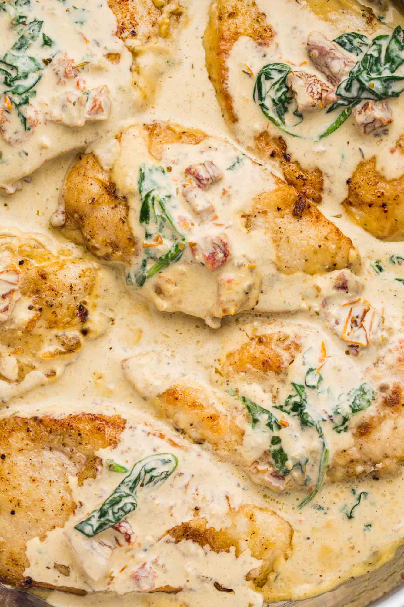Overhead shot of Tuscan chicken in a cream sauce in a stainless steel skillet