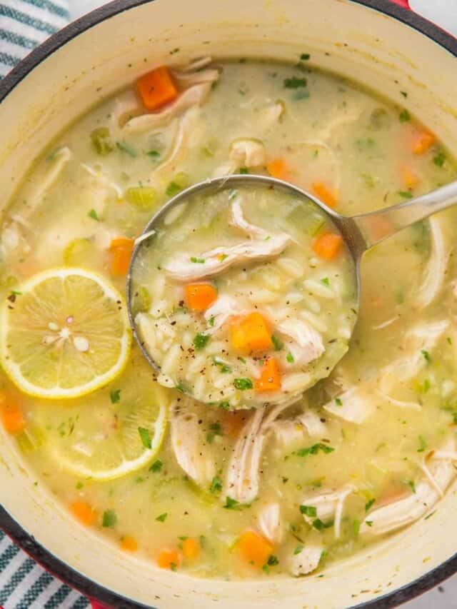 Overhead shot of lemon chicken orzo soup in a dutch oven with a ladle.
