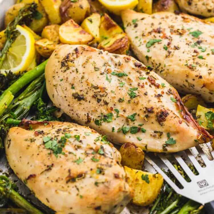 Close up shot of baked chicken and potatoes with broccoli on a sheet pan