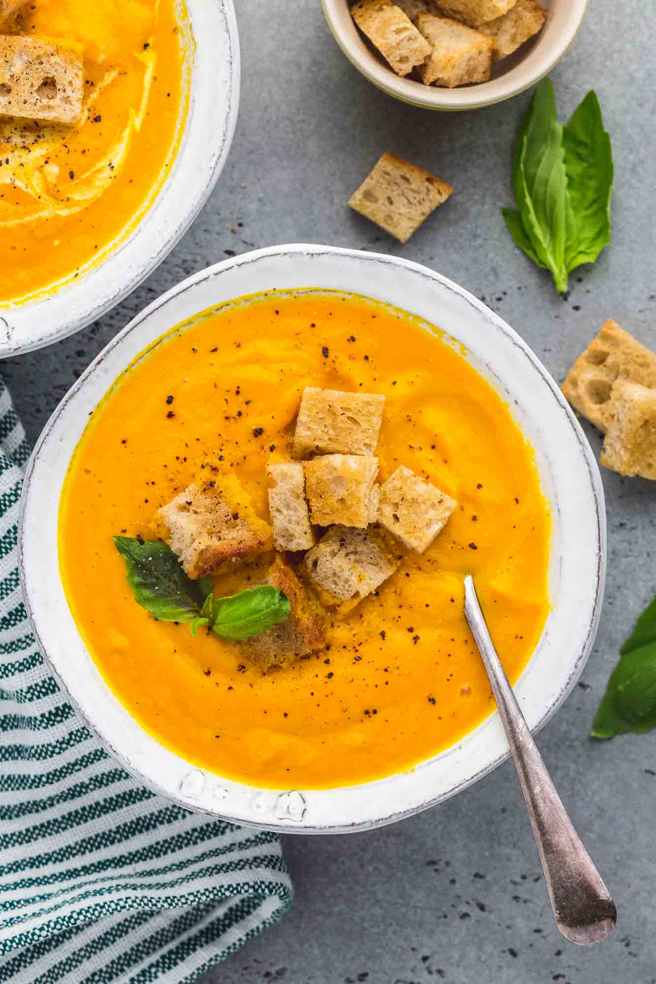 Overhead shot of 2 bowls of carrot soup with croutons
