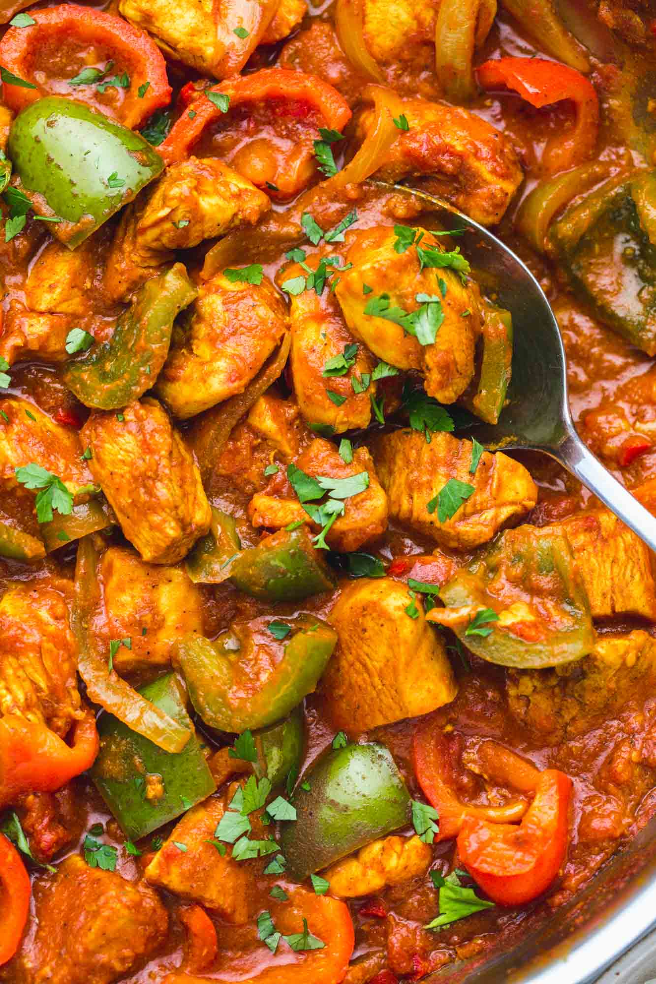Overhead shot of chicken jalfrezi in a skillet with a serving spoon