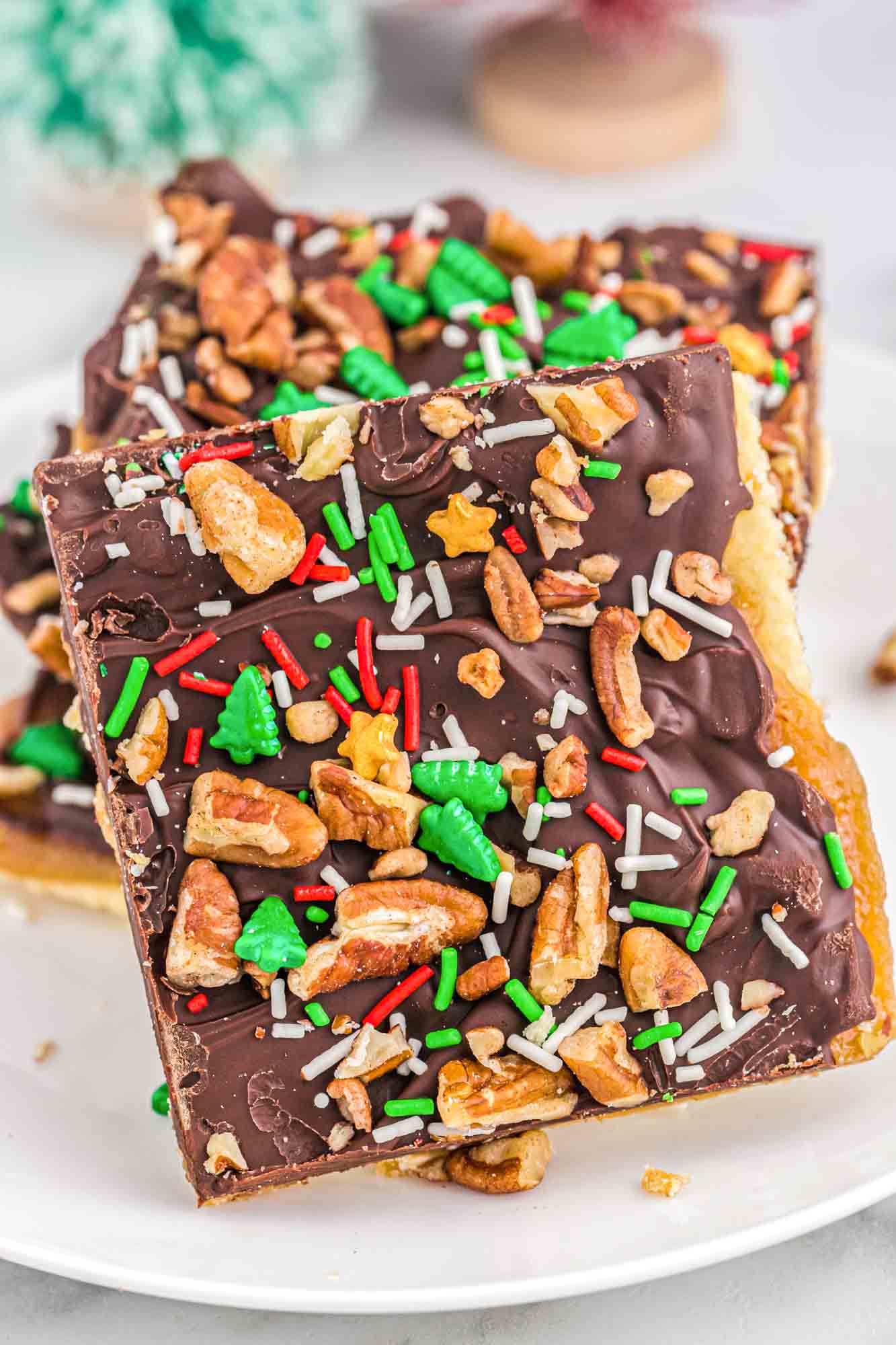 Saltine toffee cracker pieces on a white plate, decorated with holiday sprinkles