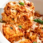Taking a slice of melty cheese lasagna out of a white crockpot