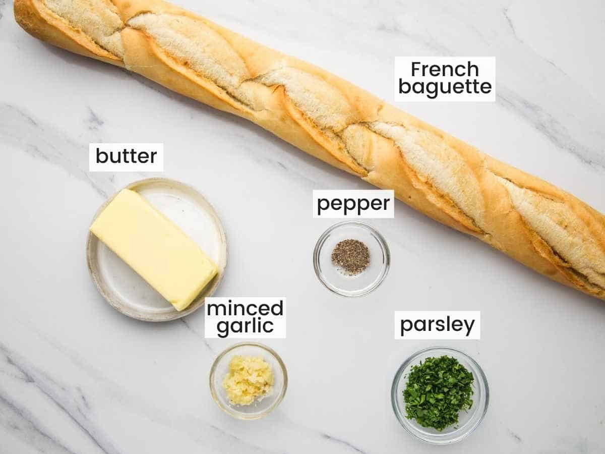 Ingredients needed to make garlic bread including French bread, butter, garlic, parsley, ground black pepper.