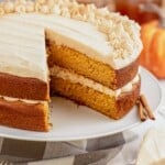 Pumpkin layer cake on a cake stand, frosted with cream cheese frosting