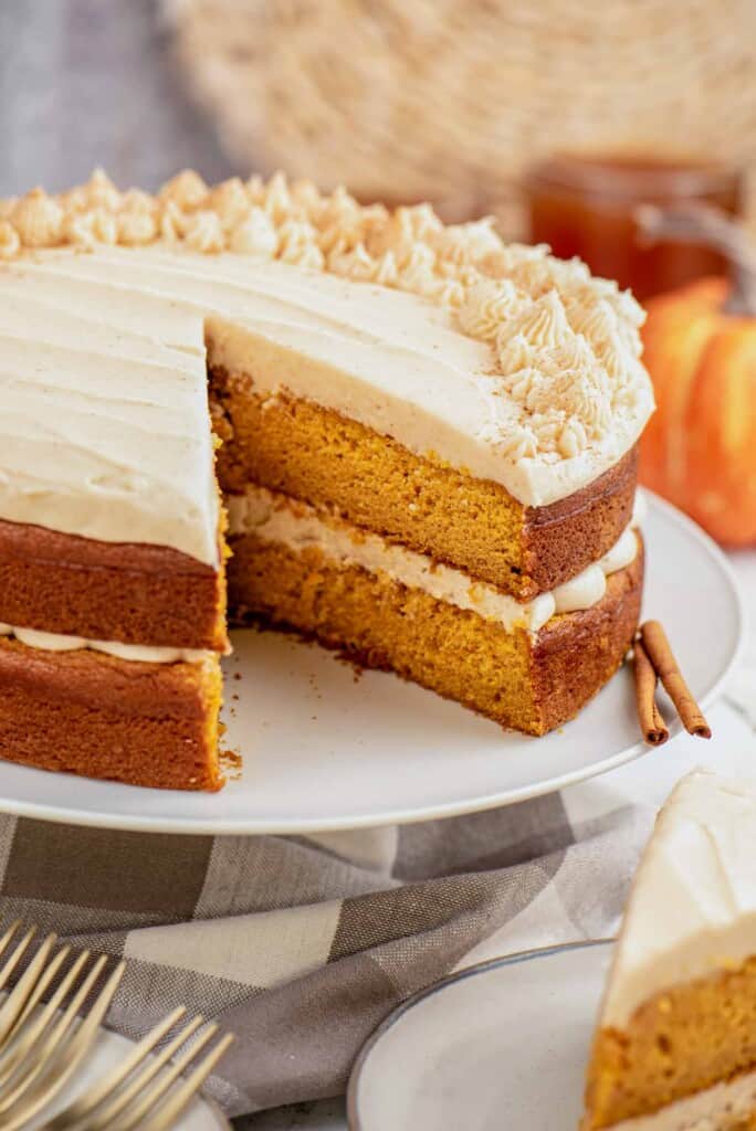 Pumpkin layer cake on a cake stand, frosted with cream cheese frosting