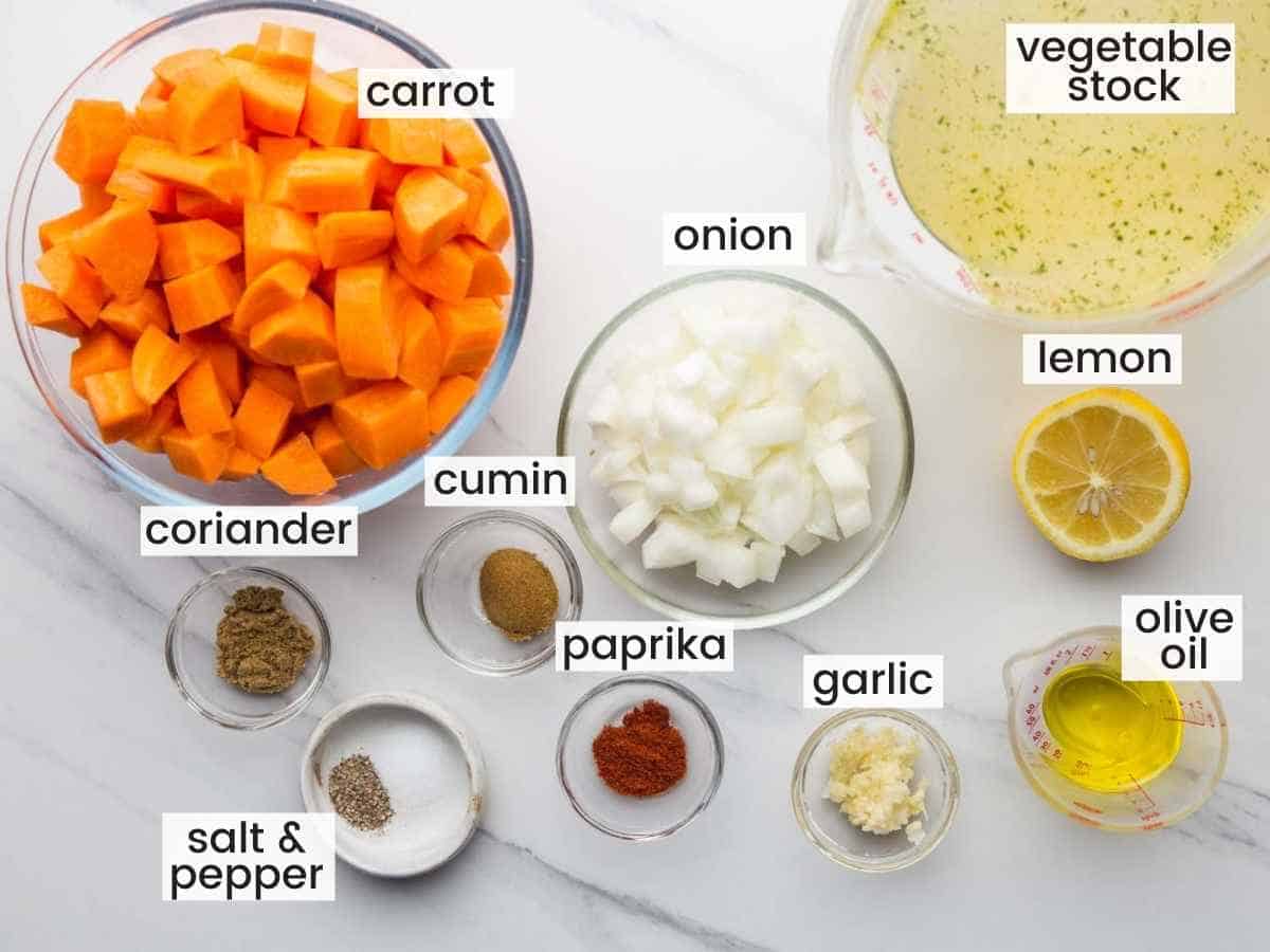 Ingredients needed to make carrot soup including carrots, stock, onion, garlic, and seasonings.