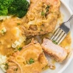 Slow cooker pork chops in a white plate served with mashed potatoes and broccoli