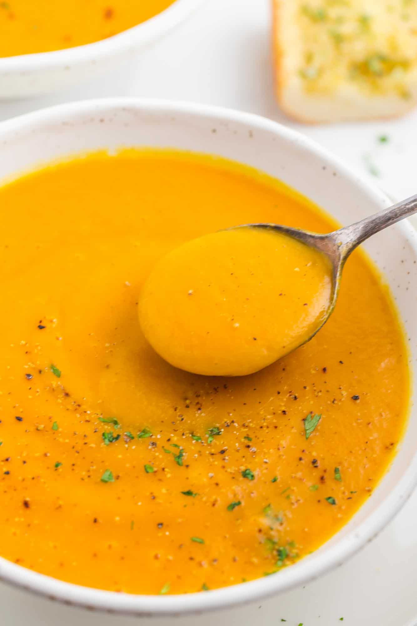 Taking a spoonful of smooth and creamy sweet potato soup, a close up shot
