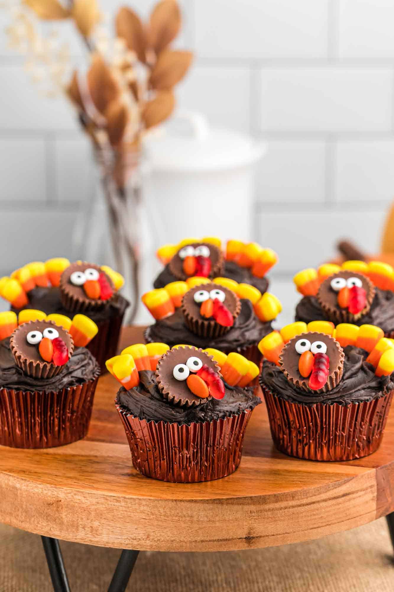 Seven turkey decorated cupcakes on a wooden tray