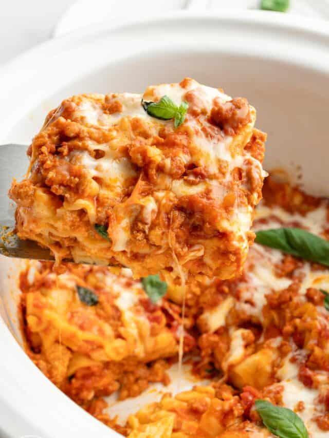 Taking a slice of melty cheese lasagna out of a white crockpot