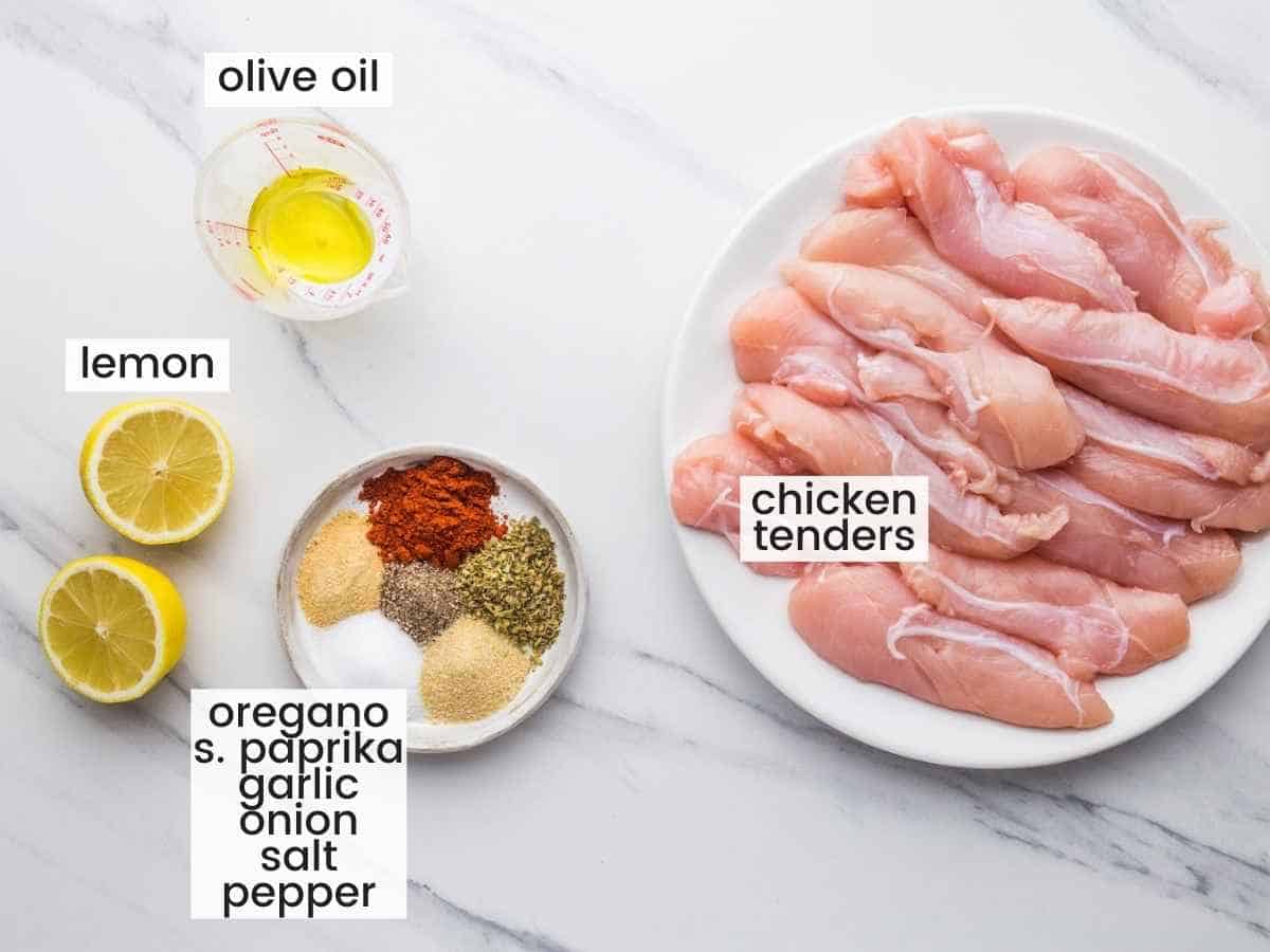 Ingredients needed to make air fryer chicken tenders,  including chicken tenders, lemon juice, olive oil, and seasonings.