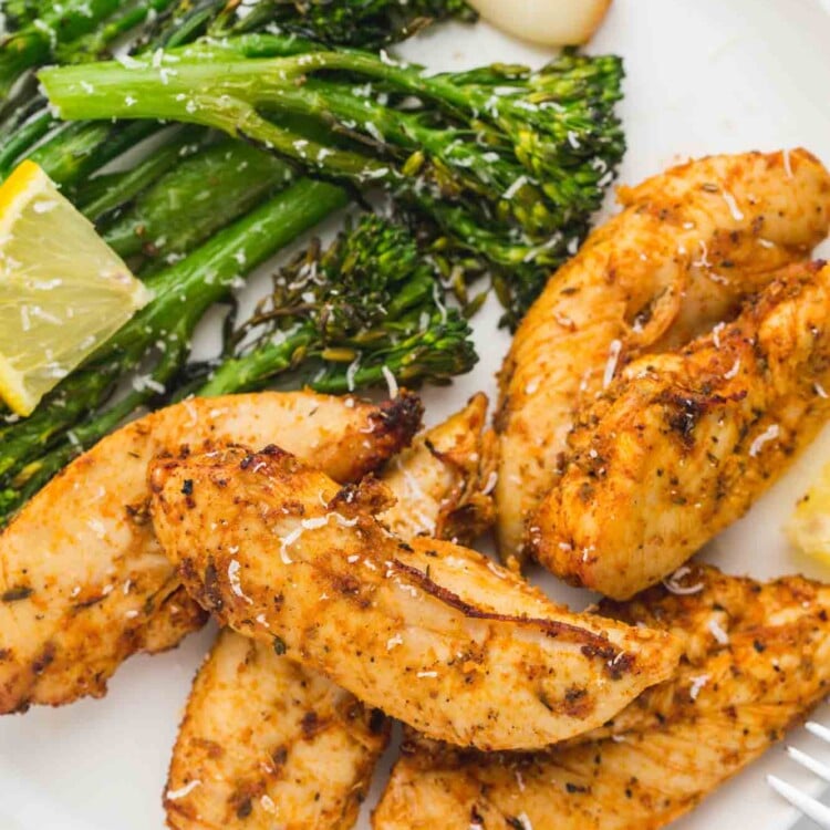 Air fried chicken tenders served with roasted broccolini on a white plate