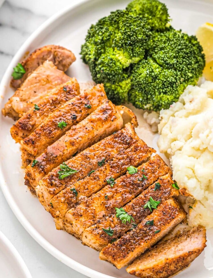 Sliced baked pork chop on a plate, served with mashed potatoes and broccoli