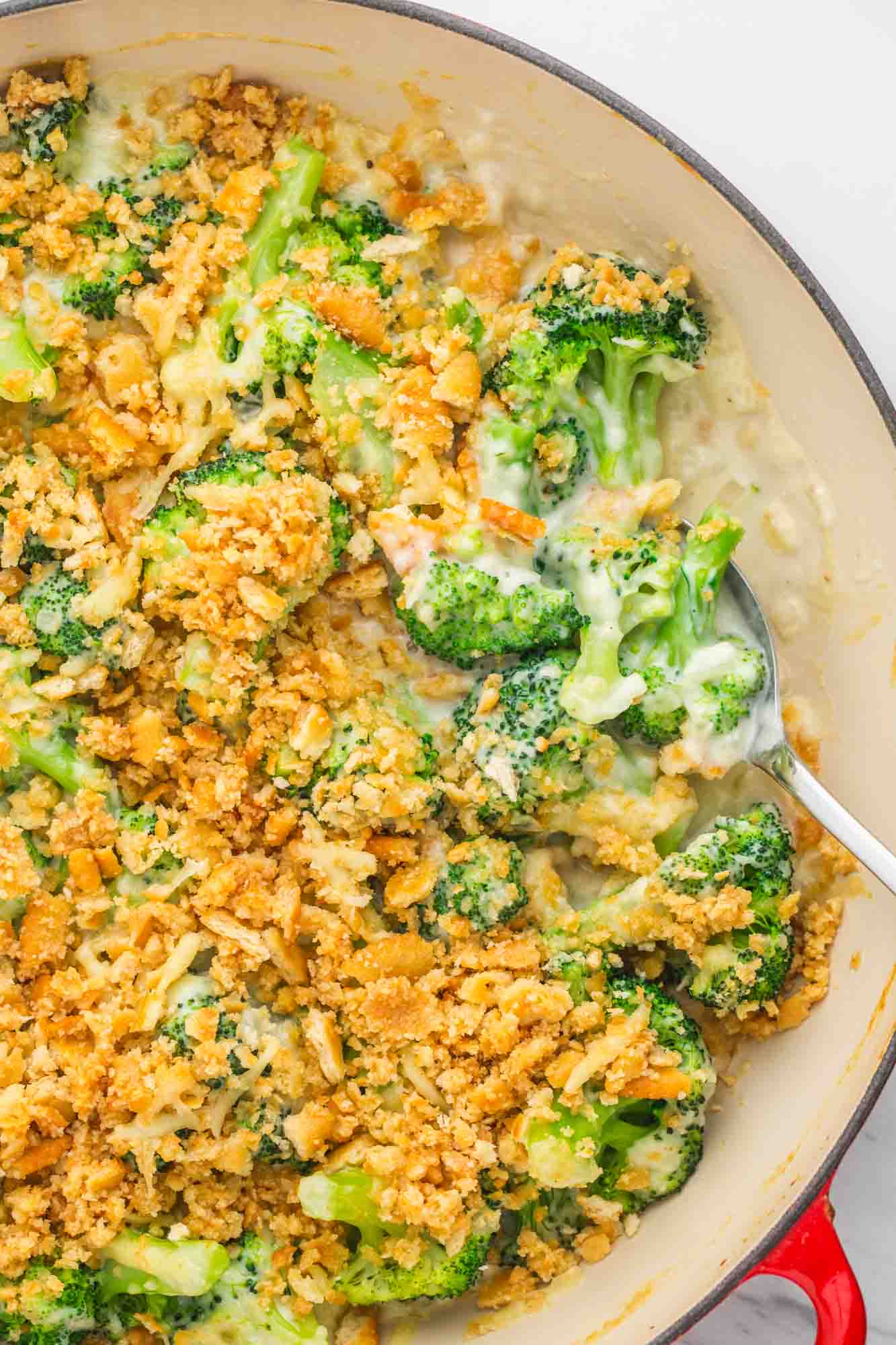 Overhead shot of broccoli casserole in a casserole cast iron dish with a serving spoon