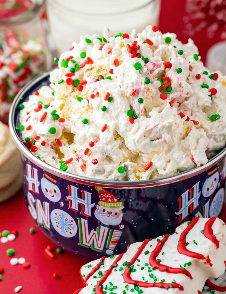 Christmas Tree Cake Dip served in a Christmas themed bowl, topped with holiday sprinkles.