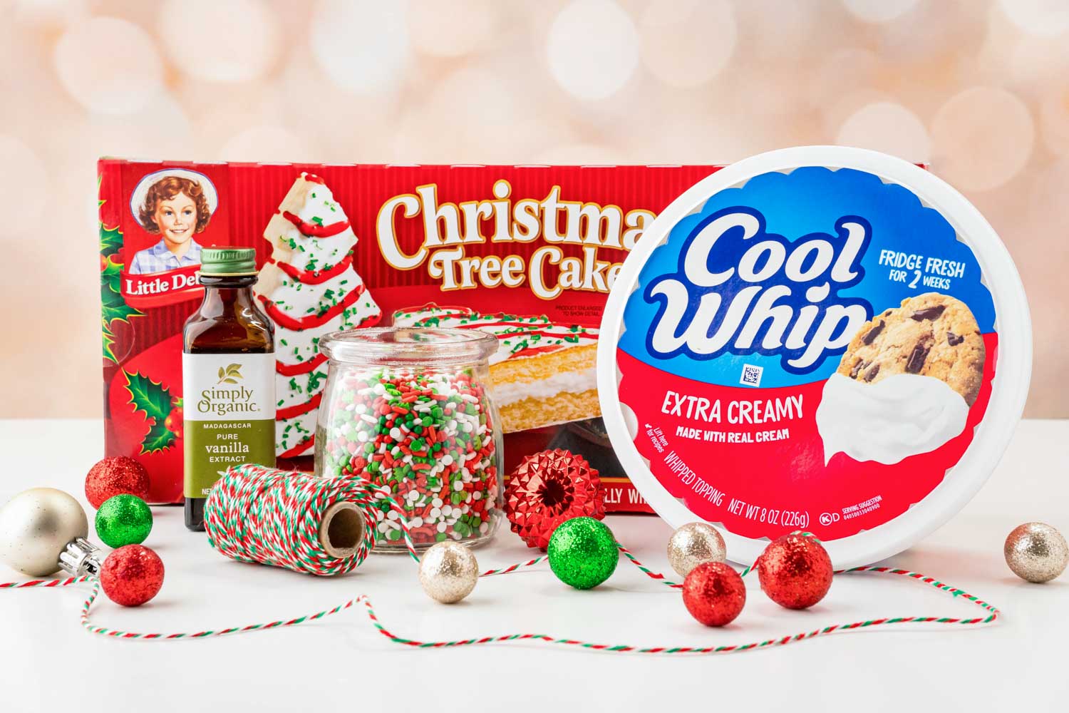Ingredients needed to make Christmas tree cake dip including little debbie tree cakes, cool whip, vanilla, and sprinkles.