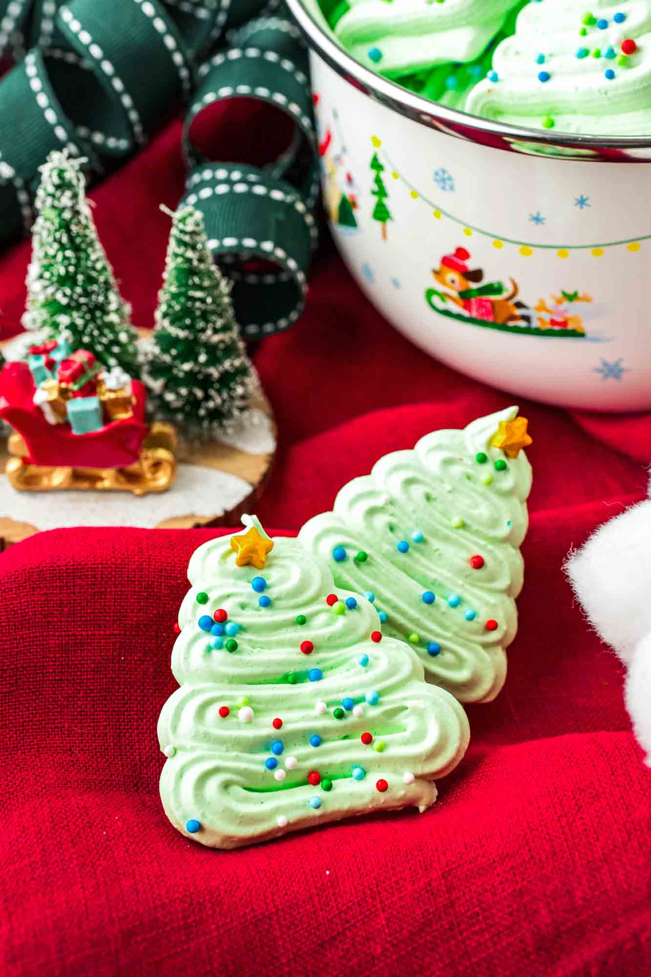 2 mini meringue christmas tree cookies on a red cloth